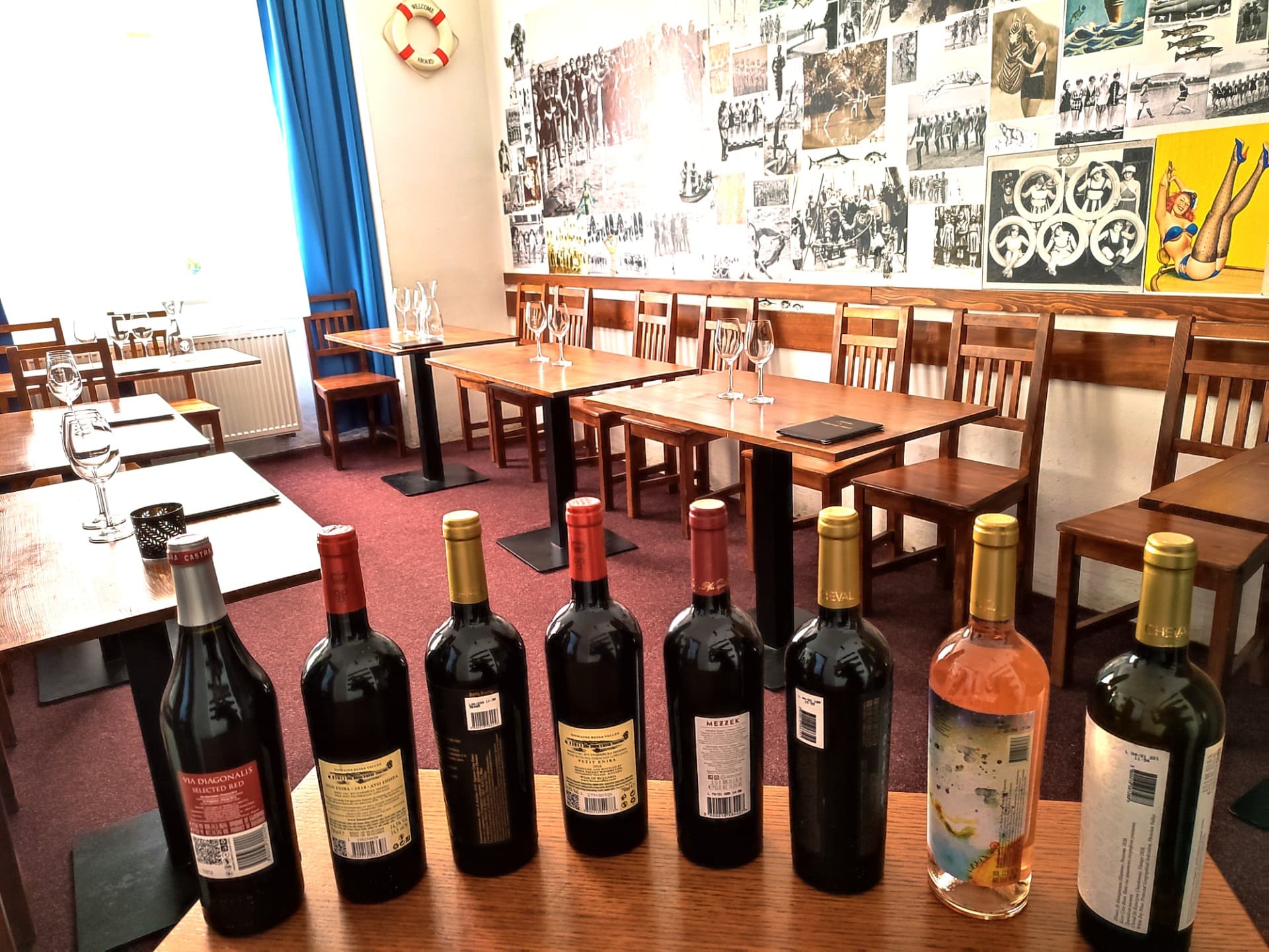 Salonek vinárny připravený na řízenou degustaci, láhve v řadě na stole