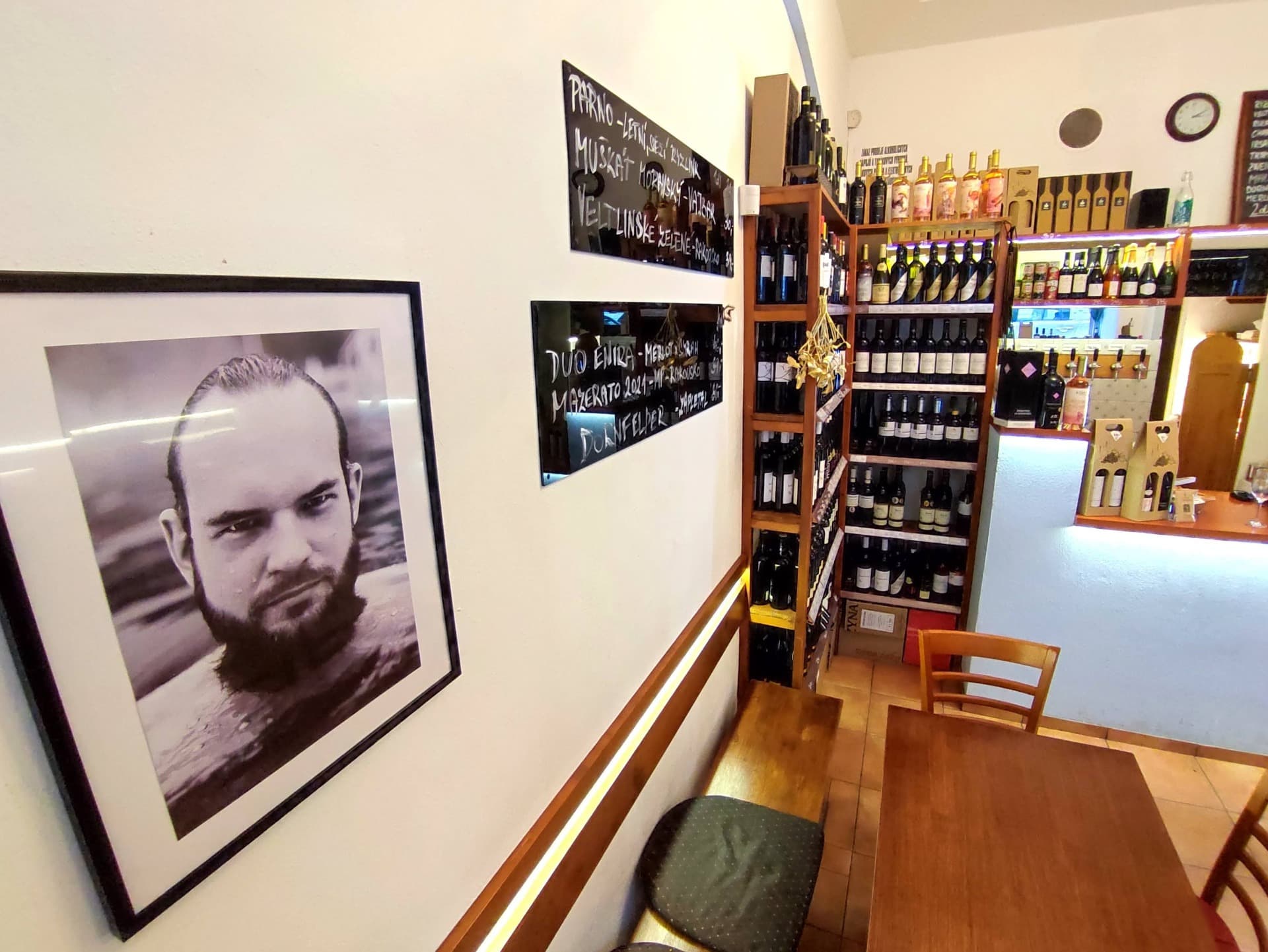 Regály s víny z Moravy i ze světa a černobílý portrét na stěně
